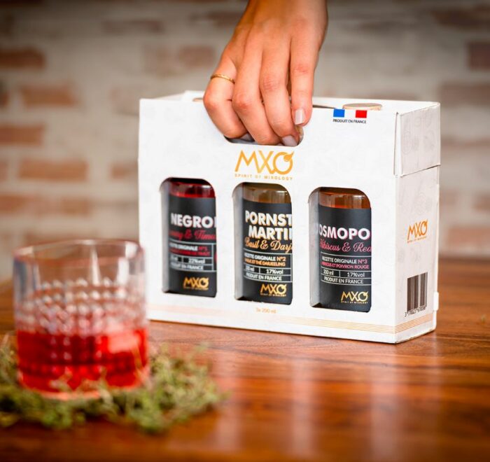 Cocktails MXO Spirit - Photo présentant les 3 cocktails en bouteille dans un coffret cadeau, qui est tenu par la hanse